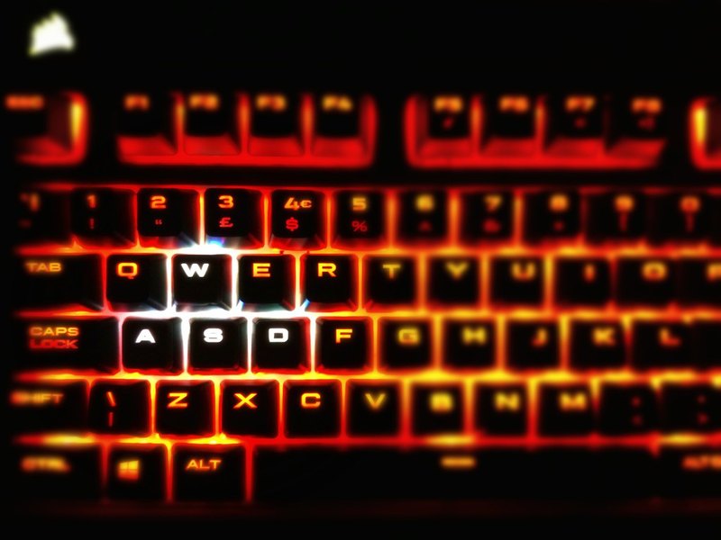 Close-up of a red backlit mechanical keyboard glowing on a dark desk
