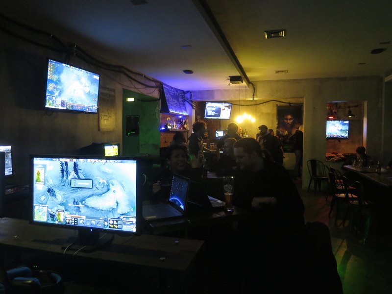 Dim NYTEGRID main hall lit only by rows of glowing gaming monitors at night