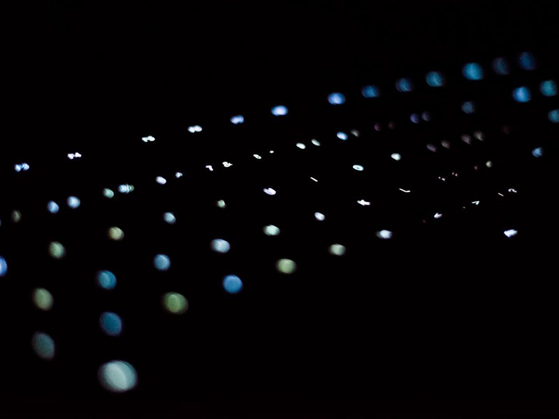 Macro detail of teal-lit mechanical keys fading into darkness